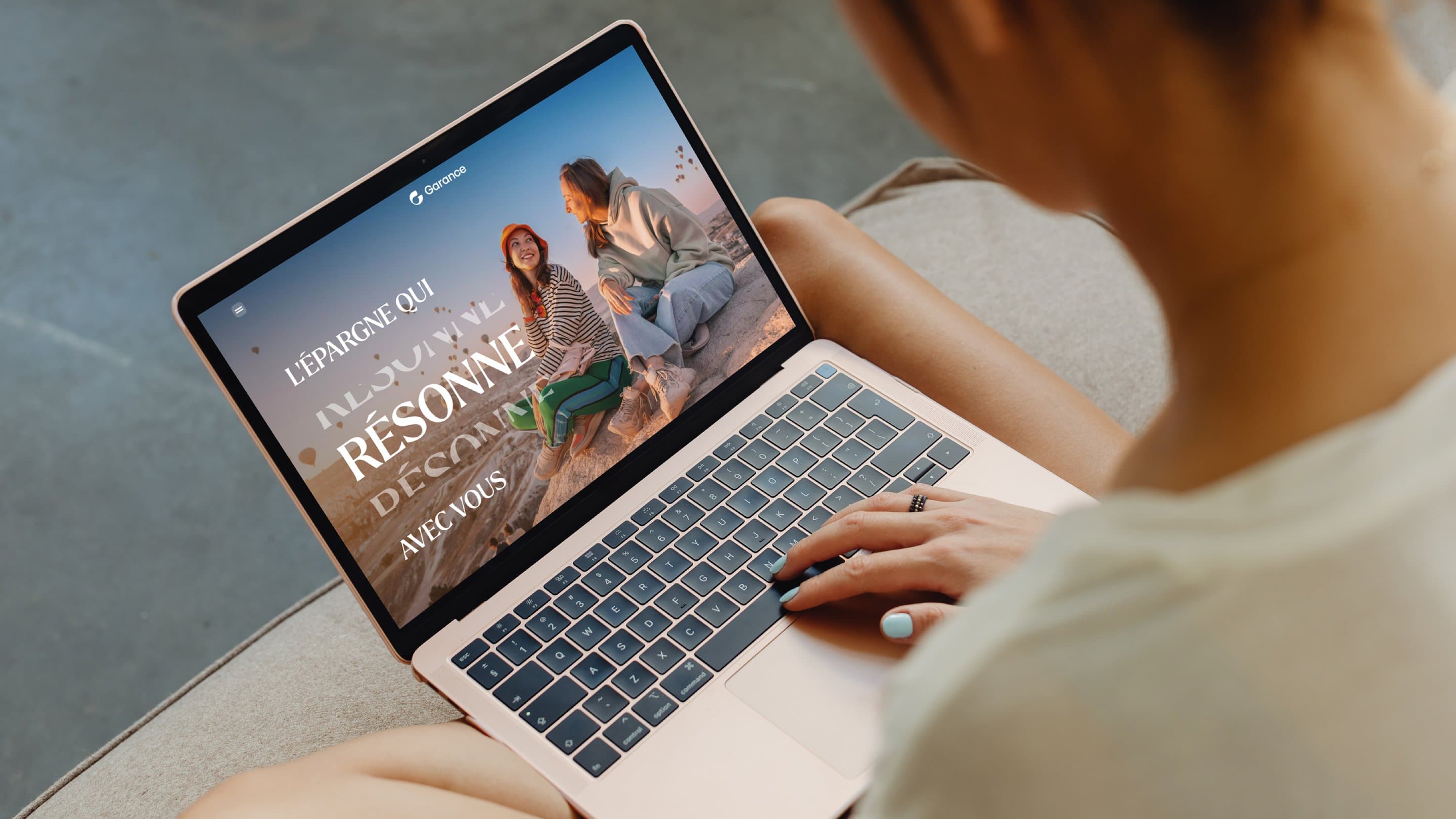 Une femme consulte la brochure Garance sur un ordinateur portable : la page d'accueil « L'épargne qui résonne avec vous » remplit l'écran
