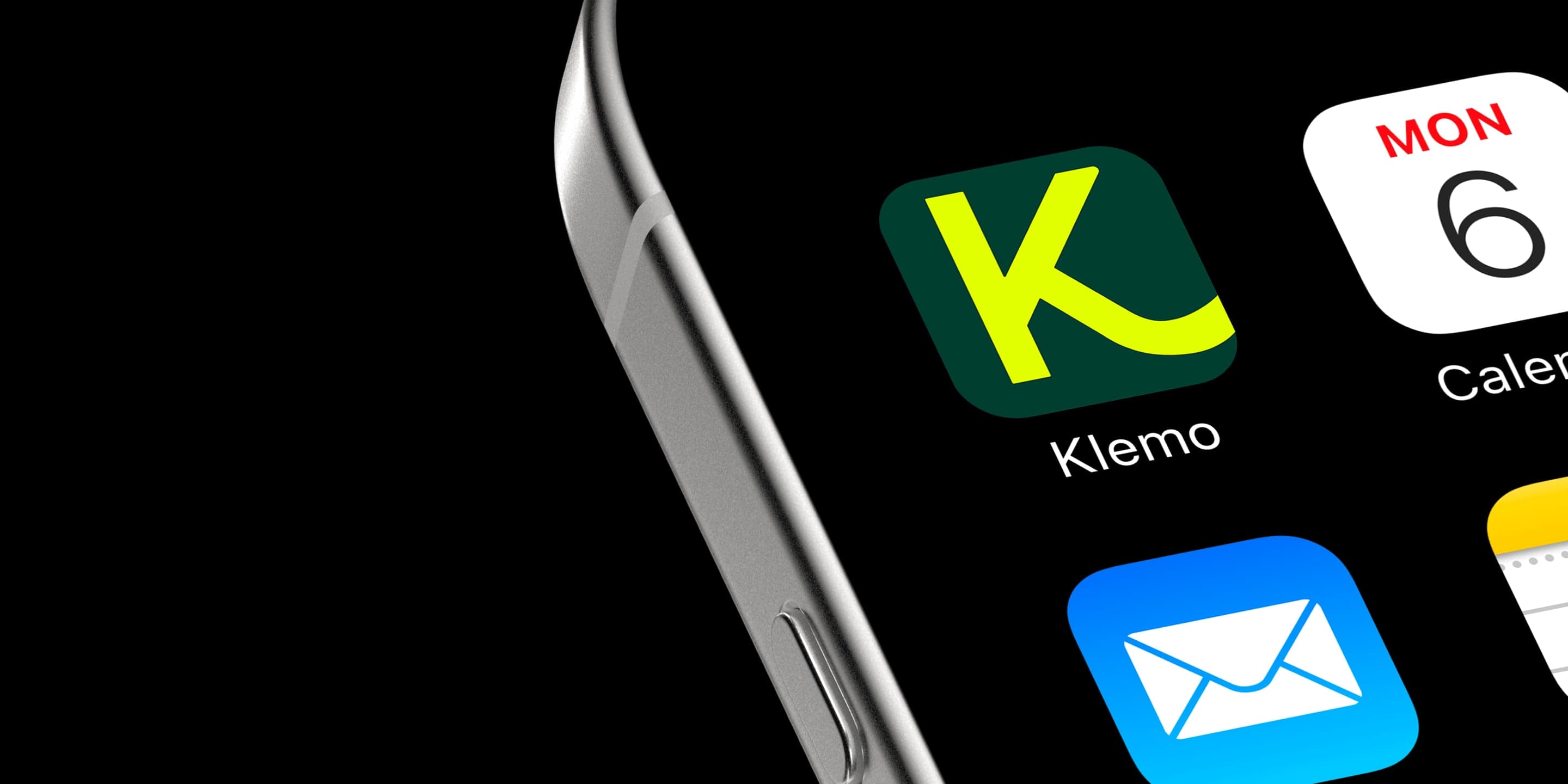 L'écran d'accueil d'un iPhone vu de biais, en gros plan : l'icône verte et jaune de l'application Klemo à côté de Calendrier, avec Mail en dessous