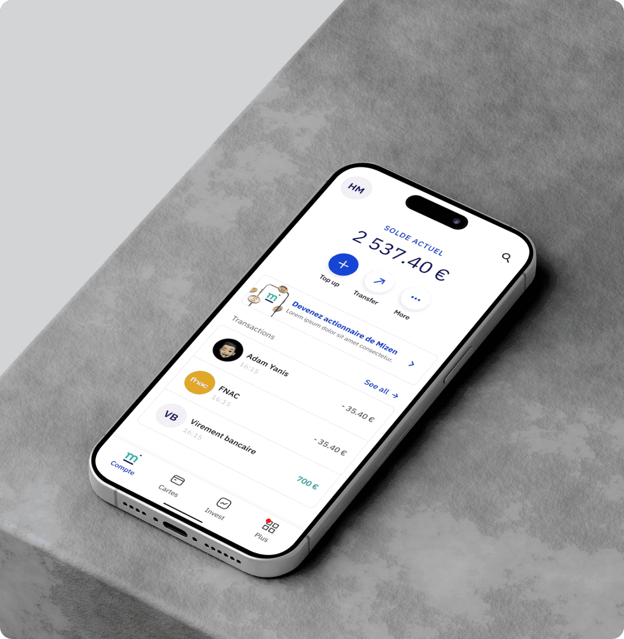 Un iPhone posé de biais sur un socle gris, affichant l'écran Compte de Mizen : le solde actuel de 2 537,40 € et les dernières transactions