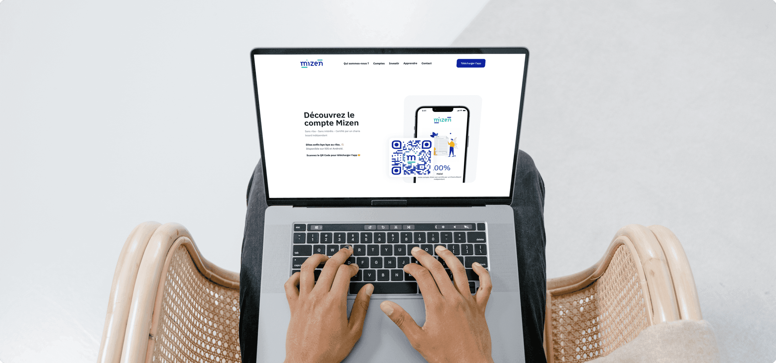Un ordinateur portable posé sur les genoux, ouvert sur le site Mizen : « Découvrez le compte Mizen », avec un QR code pour télécharger l'application sur iOS et Android